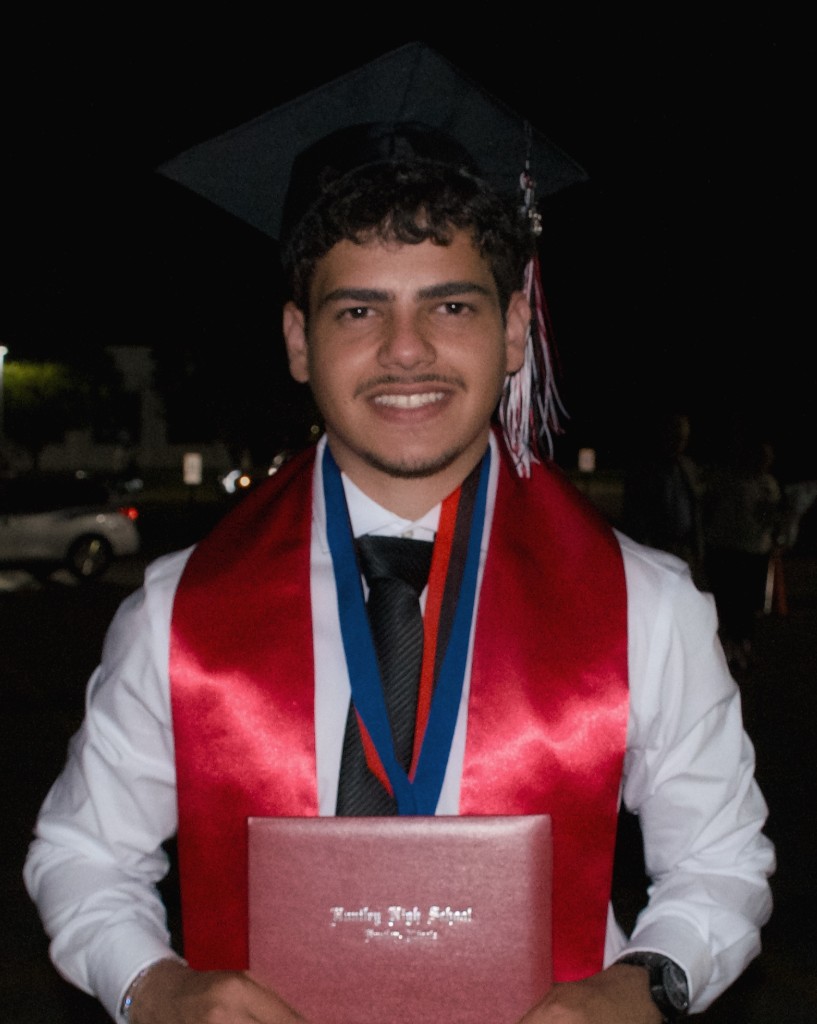 Kerellos Abdelmalak in graduation cap and gown holding a diploma
